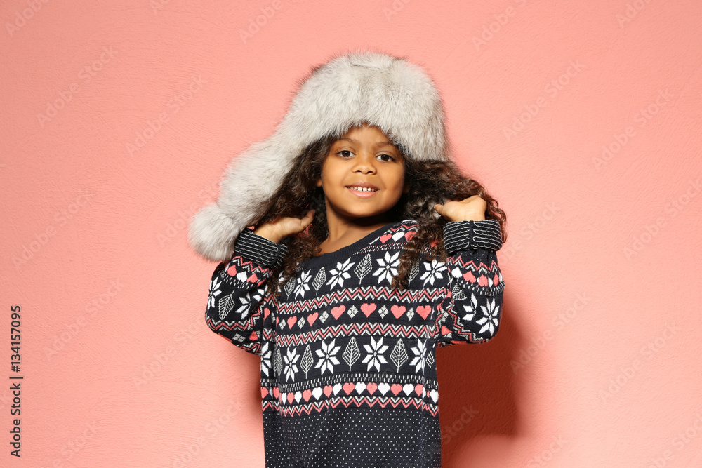 Cute little African American girl in fur hat against pink wall. Fashion concept Cute little African American girl in fur hat against pink wall. Fashion concept