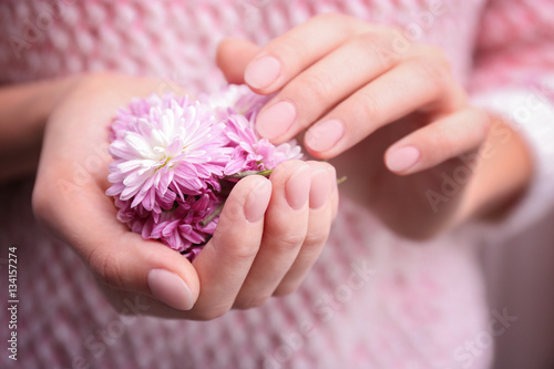 Female hands with beautiful nail art holding flower, closeup