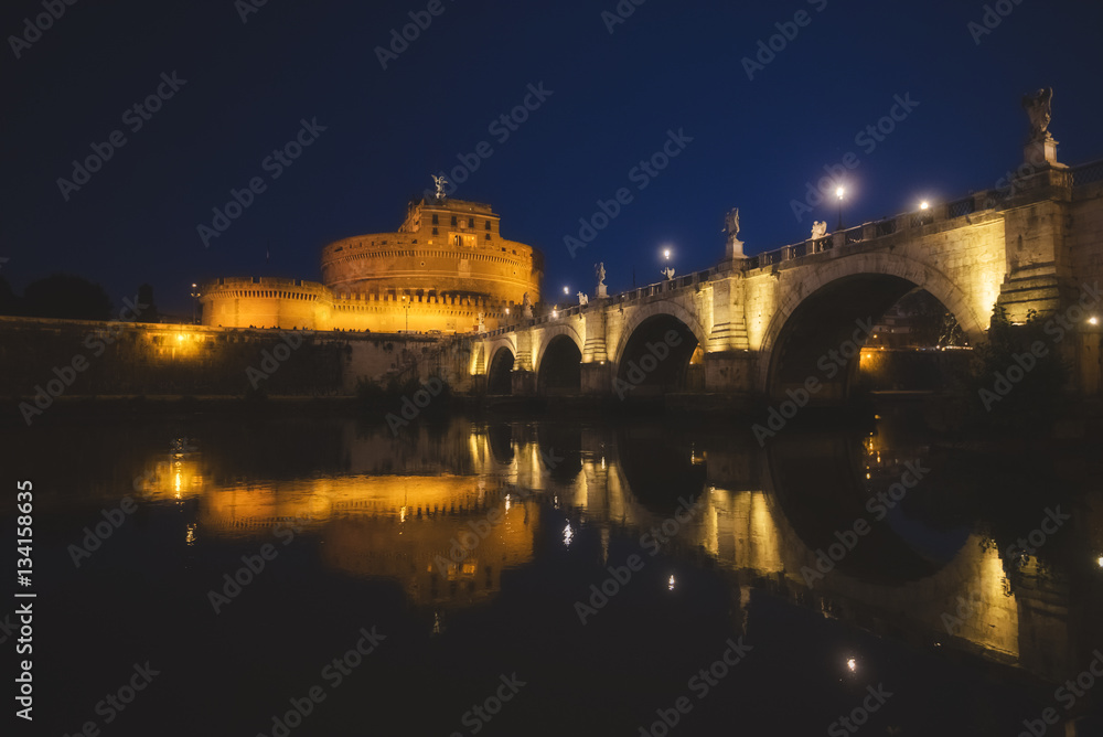 Puente hacia el Castillo de San't Angelo, de noche con iluminación de farolas y con reflejos en el río Tiber. Roma, Italia