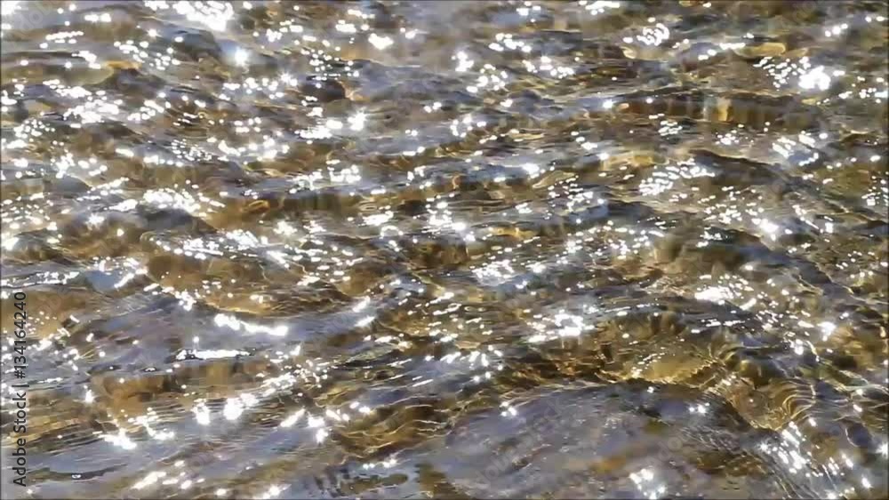 sun reflections on flowing water over stones

