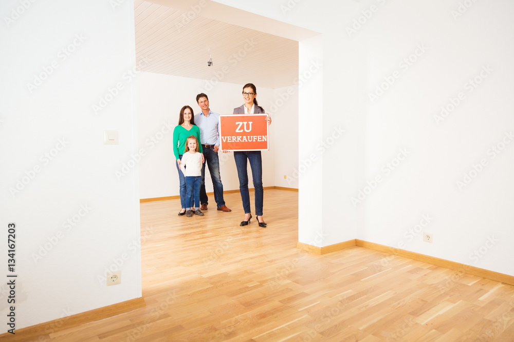 Realtor In Empty Apartment, Holding 'zu Verkaufen' Sign