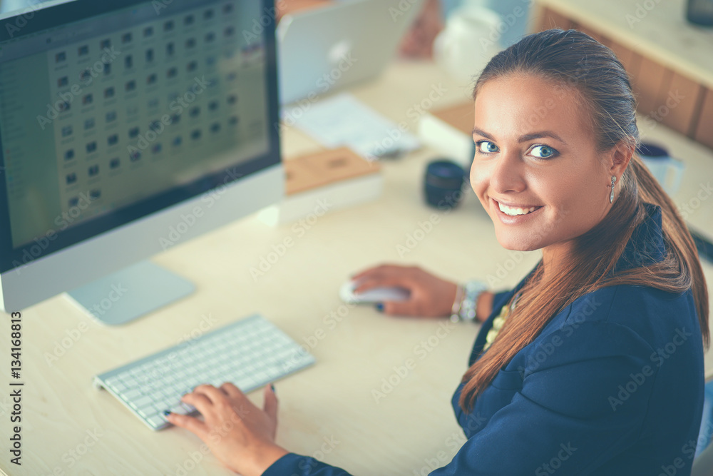 Young woman working in office, sitting at desk Young woman working in office, sitting at desk