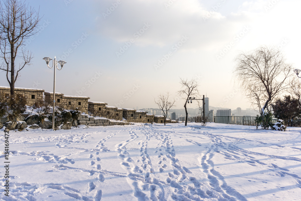 naksan park stone wall covered in snow with the view of the city in the back. Taken in Seoul, South Korea naksan park stone wall covered in snow with the view of the city in the back. Taken in Seoul, South Korea