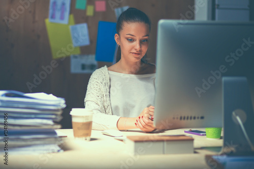 Young woman working in office, sitting at desk