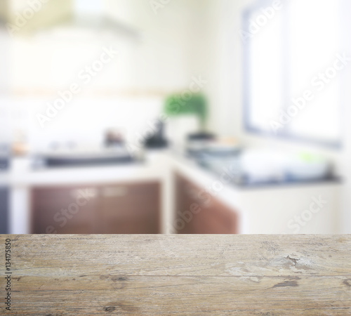 wooden table top with blur of work top and utensils in modern kitchen
