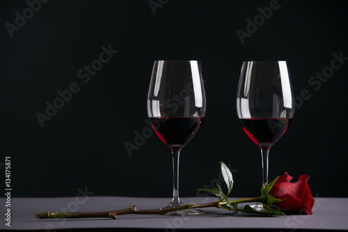 Two wineglasses with red rose on a dark background. Valentine's day theme concept