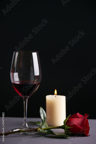 Wineglasse with red rose and candle on a dark background. Valentine's day theme concept
