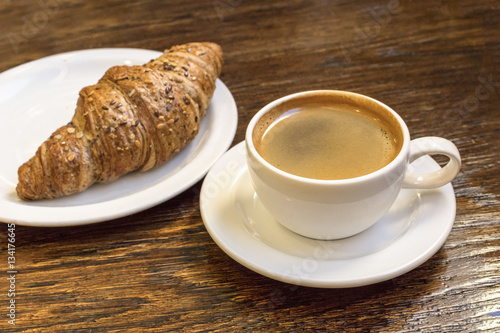 Fototapeta Naklejka Na Ścianę i Meble -  Cup of dark coffee with cereal croissant