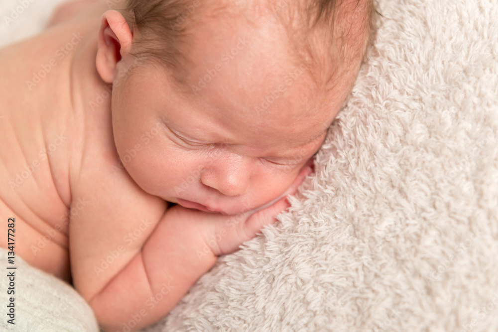 Infant pressing hands to his cheek, closeup Infant pressing hands to his cheek, closeup
