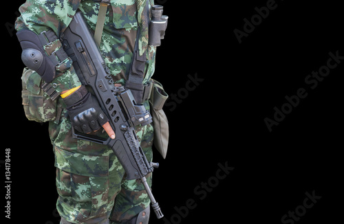 soldier in uniform holding automatic assault rifle on black background photo