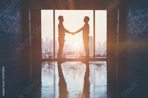 Businessmen handshake after the trade agreement in office on the building.
(silhouette) photo
