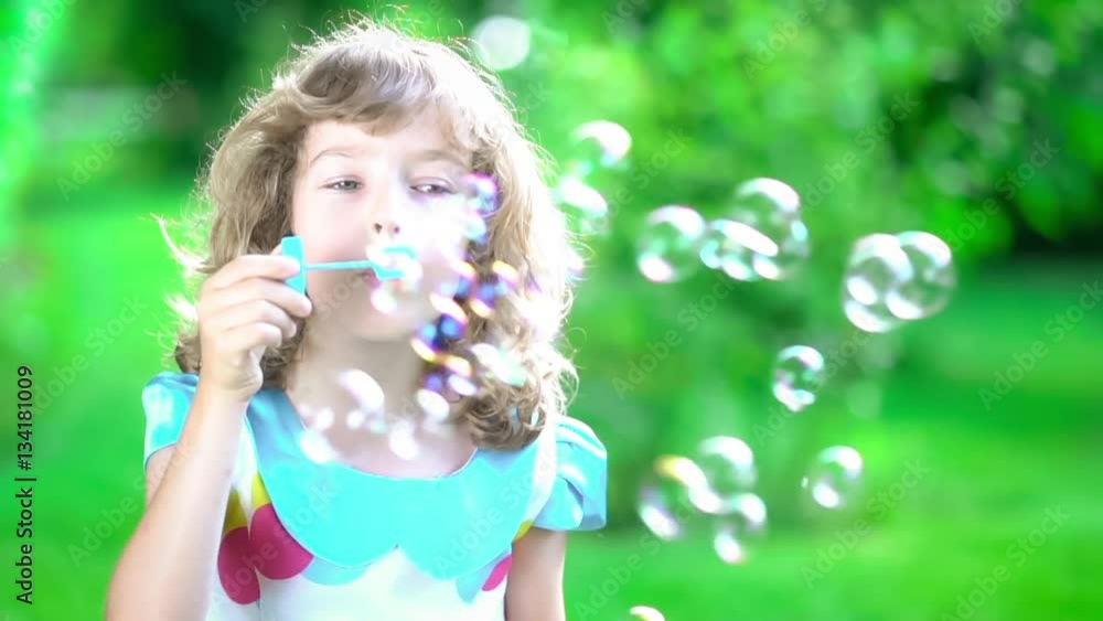 Happy child blowing soap bubbles in spring park. Kid having fun outdoors. Imagination and freedom concept. Slow motion from 120 fps