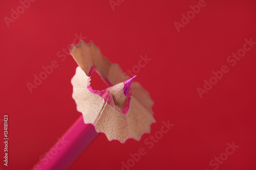 Pencil sharpener shavings on red background. Back to school