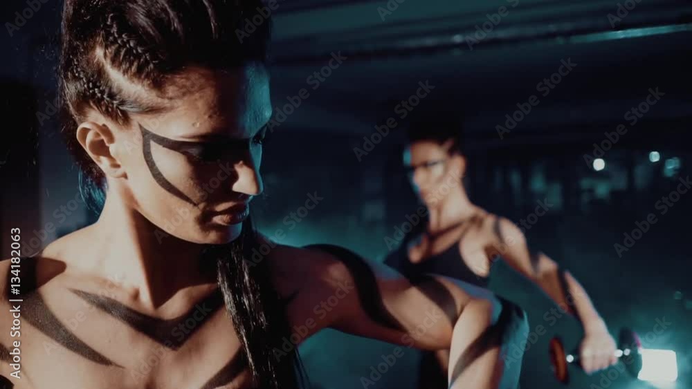 Two young athletes, muscular women training in the gym with weights close up Two young athletes, muscular women training in the gym with weights close up