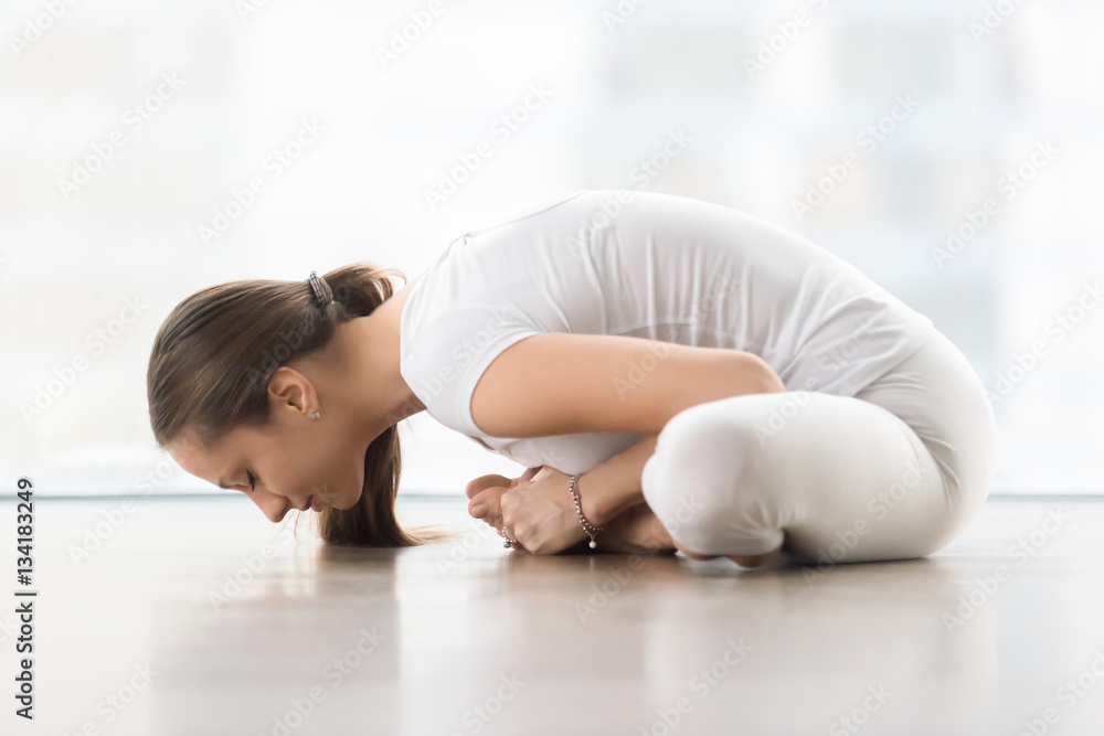 Young sporty woman practicing yoga, doing Butterfly exercise, baddha  konasana pose with props in white room. Indoor full length Stock Photo |  Adobe Stock