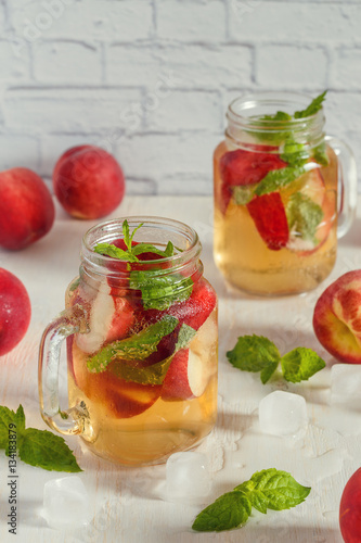 Homemade lemonade with peaches and mint leaves.