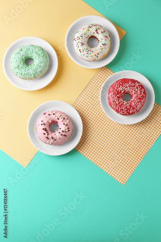 Plates with delicious donut on colorful background