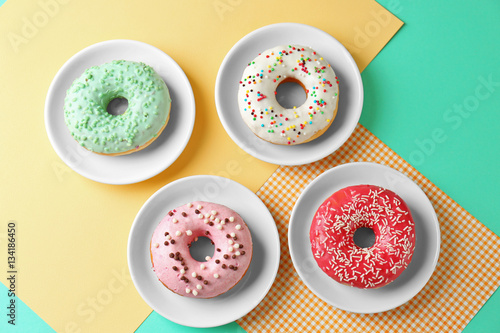 Plates with delicious donut on colorful background