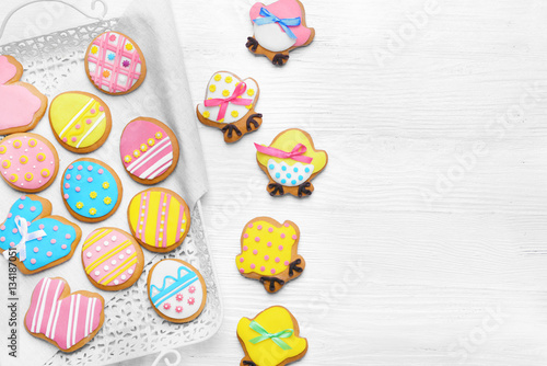 Delicious colourful Easter cookies on tray and white wooden background