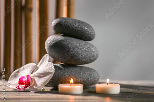 Spa still life with pebbles  candles and orchid flower on grey background