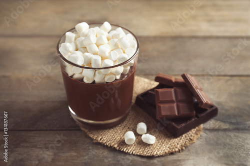 Chocolate mousse with marshmallows in portion glass on wooden background