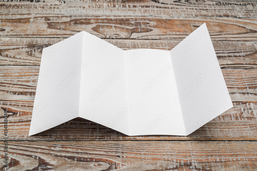 Fototapeta premium Four - fold white template paper on wood texture .