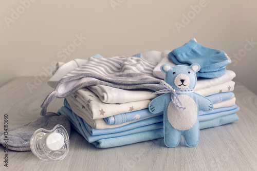 Obraz na płótnie baby clothes with diapers are stacked with a pacifier and a toy bear w salonie