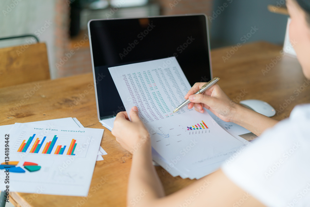Business woman hand with Financial charts and laptop on the tabl Business woman hand with Financial charts and laptop on the tabl
