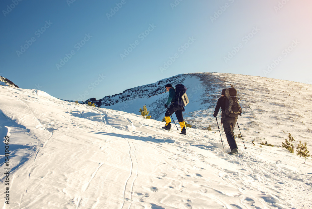hikers traveling on snowy mountains to the top at sunset