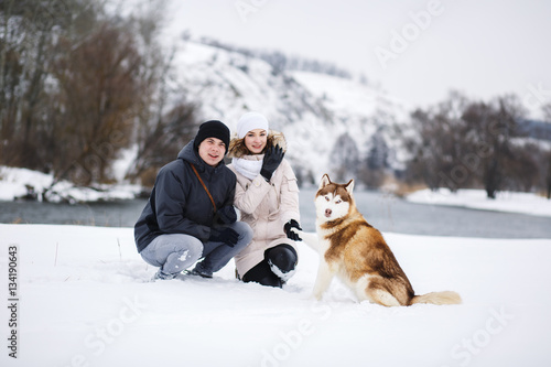 A young pregnant couple walking in the woods with the dog red Husky. photo