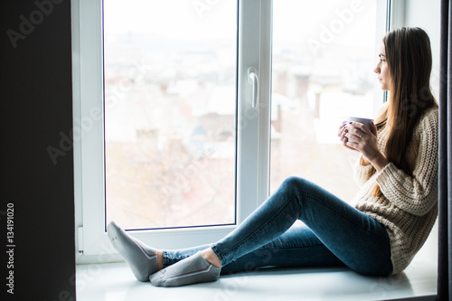 Young beauty woman drink coffee near window at home
