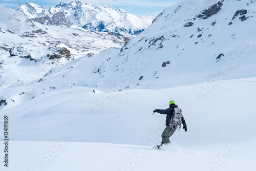 FORMIGAL, SPAIN - JUNE 20, 2017: a mountain skier goes downhill through a snowy valley in the vicinity of Formigal, Tena Valley, Spanish Pyrenees.