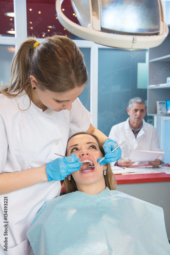 Young woman on medical exam at dentist office. Dentist in the background. Young woman on medical exam at dentist office. Dentist in the background.