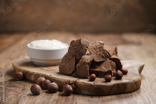 chunks of gianduja with hazelnuts and cream on wood board, premium chocolate dessert photo