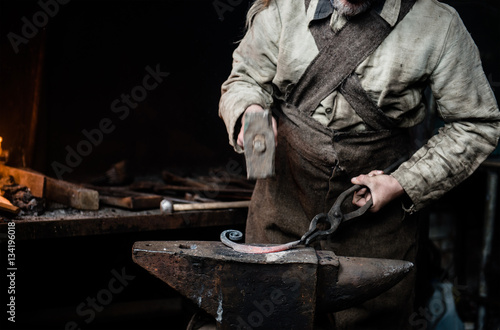 Fotografia closeup hands of the village smithy, pulling the metallic articl