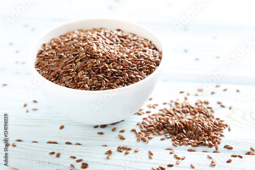 Brown flax seeds on white wooden table