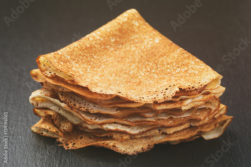 thin crepes or blinis folded in triangles on slate board, vintage toned