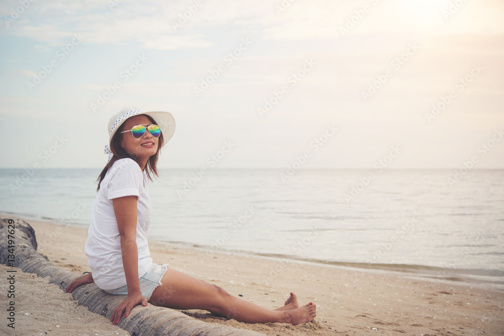 Young beautiful woman sitting on the beach wearing sunglasses. F