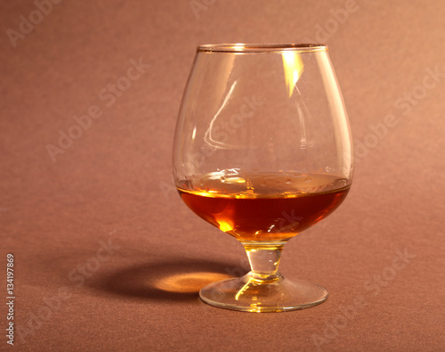 White cup of coffee and cognac in a glasses, pralines on red background.