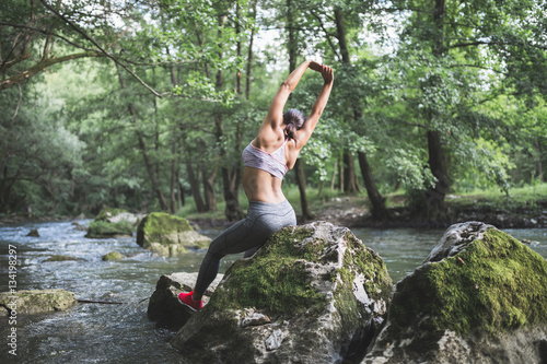 Fitness and active life theme. Attractive young woman doing stretching exercises in beautiful untouched nature environment.