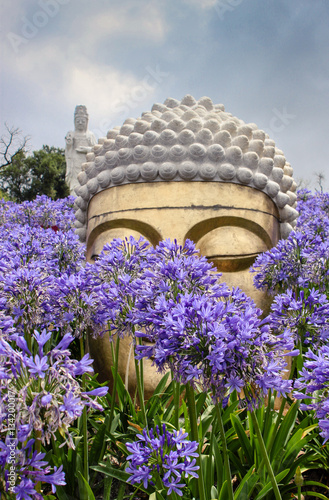 Amazing Sculptured Buddha surrounded by flowers photo