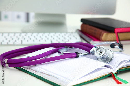 Stethoscope lying on a table an open book