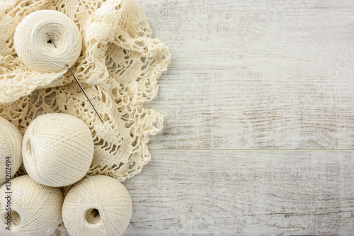 crochet tablecloth, crochet hooks and balls of cotton thread on a white wooden table. top view, copy space