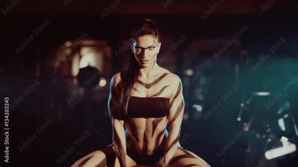 Female bodybuilder lifting chains isolated on dark Female bodybuilder lifting chains isolated on dark