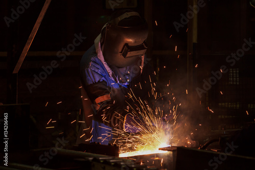 Worker welding steel in car factory 