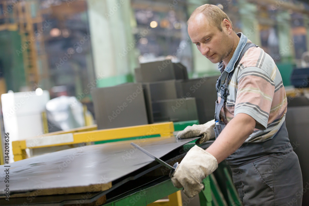 Factory Man Worker Removing Metal Burrs from Steel Sheet with Deburring Tool at Workshop Factory Man Worker Removing Metal Burrs from Steel Sheet with Deburring Tool at Workshop