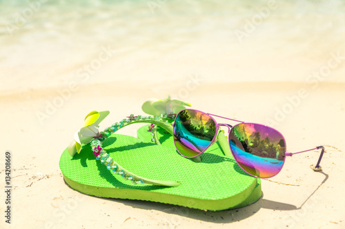 Tropical vacation concept—Green flip-flops and sunglasses on a