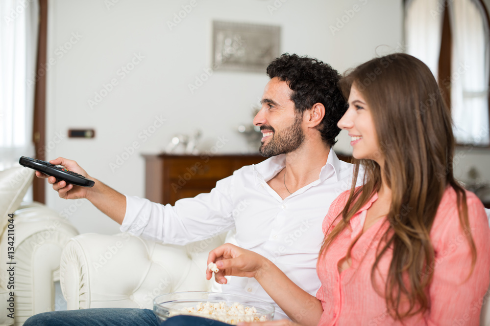 Fototapeta premium Couple using a remote control while sitting on the couch