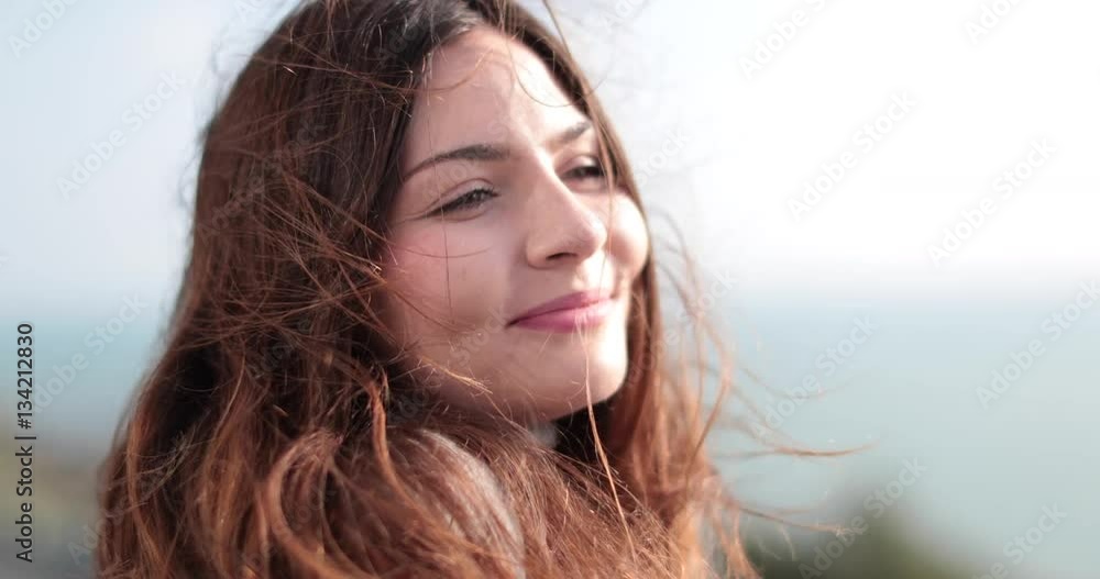 Carefree woman with wind in her hair looking to camera Carefree woman with wind in her hair looking to camera