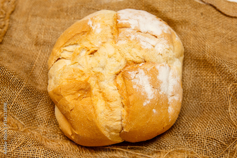 Fototapeta premium Homemade round bread from wheat flour lies on rough cloth..